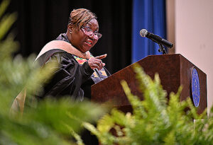 Female speaker pointing to the crowd from a podium.