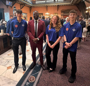 Three students pose with man in a suit.