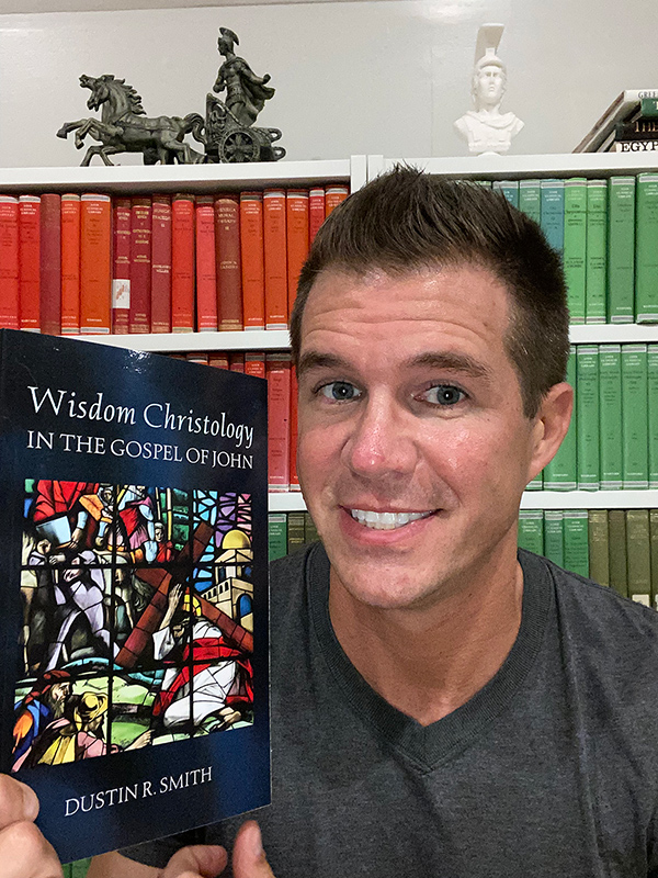 Photo of Dustin Smith holding up a book