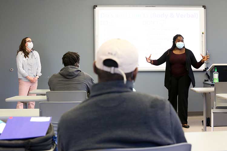 Two people presenting to a classroom