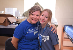 An image of a parent or caregiver embracing a child. They are posing for the camera after moving into the student's residence hall room on the SMC campus.