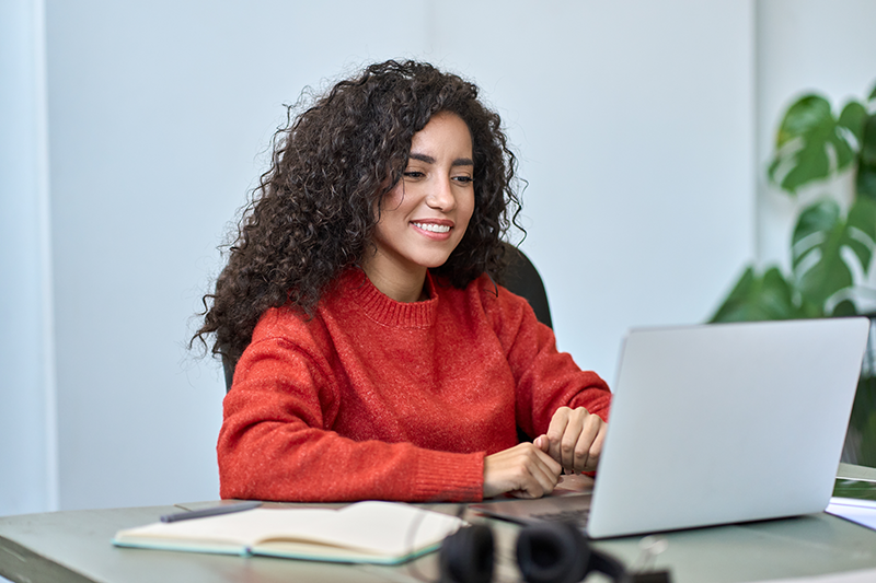 A smiling Latina student with her laptop.