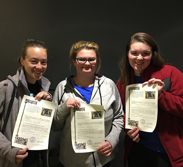 Three students holding up document