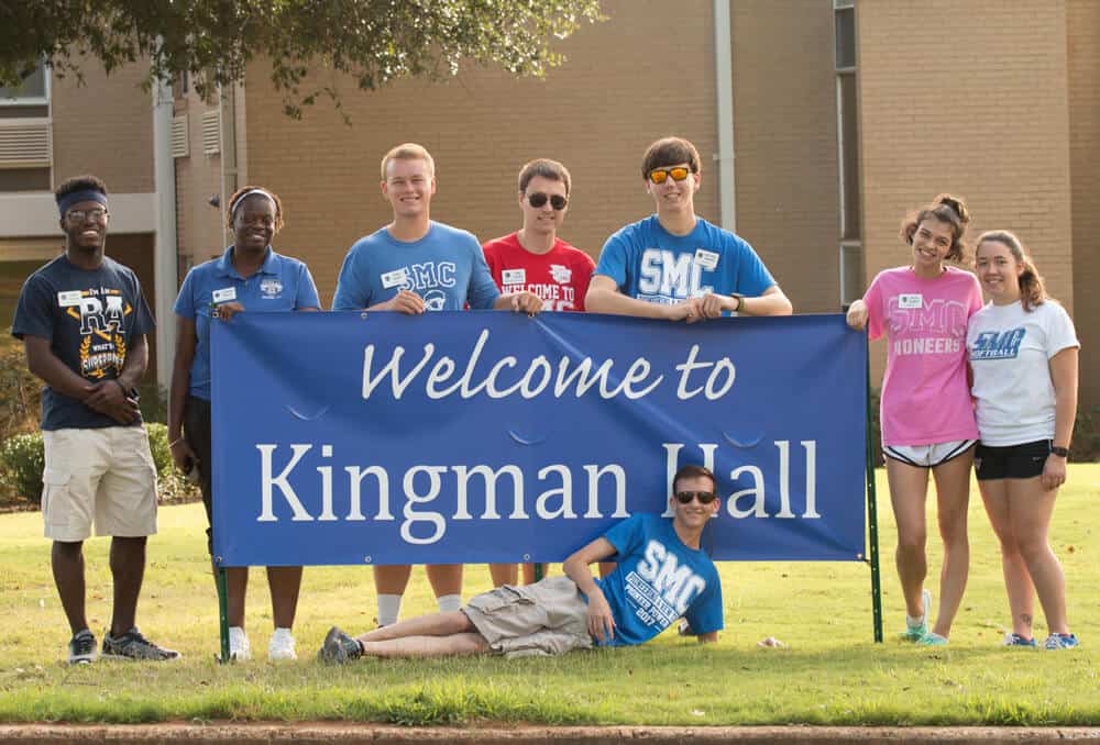 Students holding sign that says Welcome to Kingman Hall 