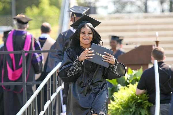 Woman walking across stage with diploma