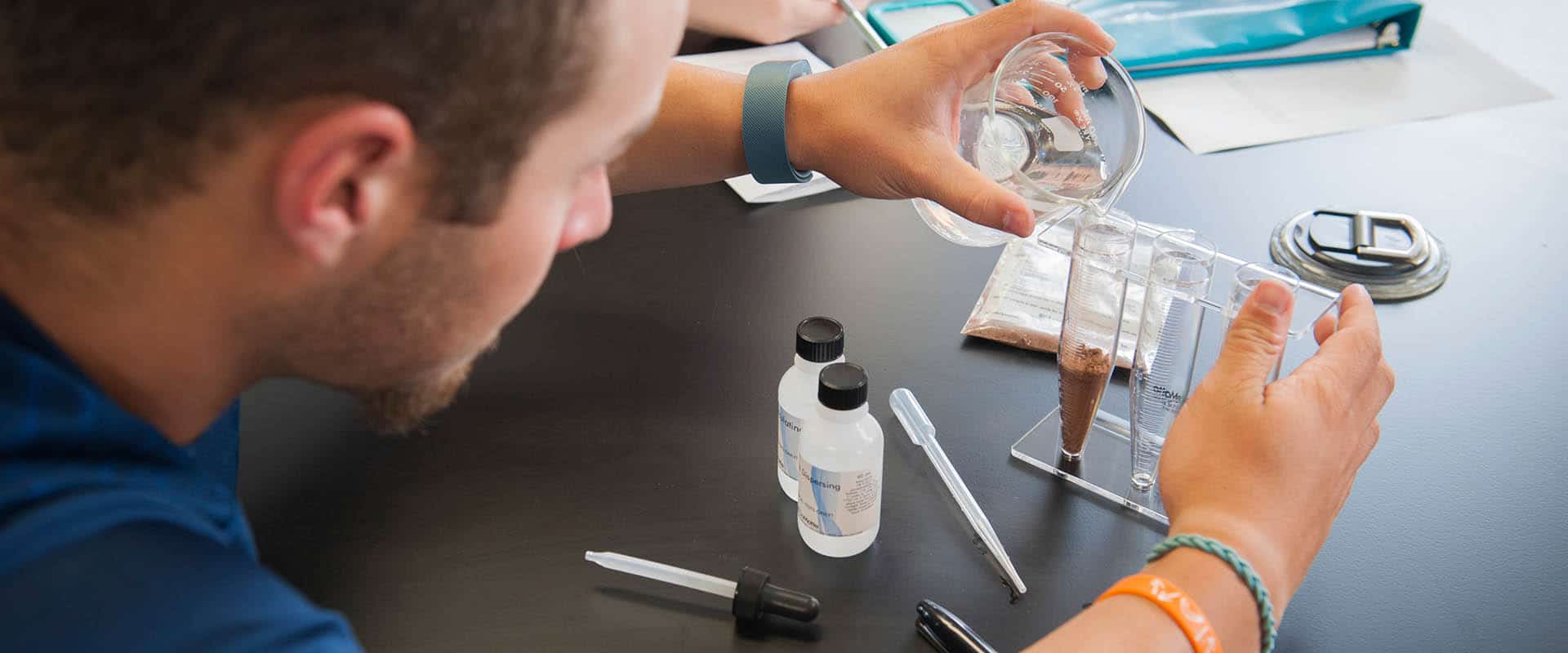 Student pouring liquid from a beaker into test tubes