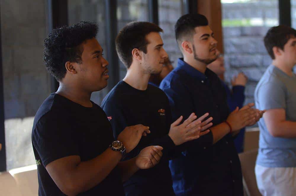 Three male students clapping to music